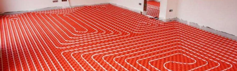 Instalace elektrického podlahového topení s červenými matemi v místnosti.