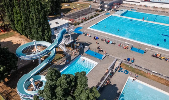 Vzdušný pohled na bazény a vodní hřiště v koupališti.
