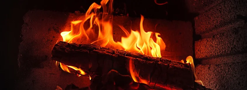 Hořící dřevo v kamne s jasnými plameny uvnitř.