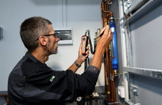 Technik opravuje plynový kotel pomocí diagnostického přístroje.
