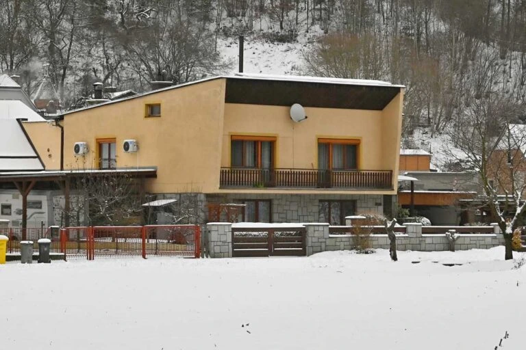 Žlutý dům v zimě s balkonem na sněžném pozadí.