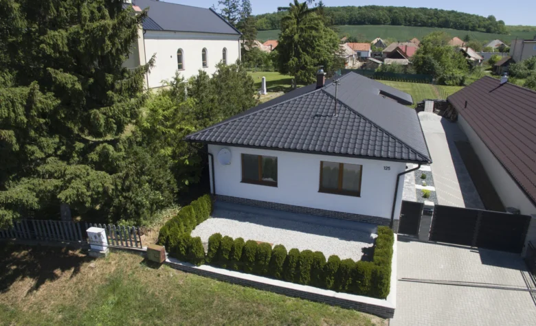 Moderní dům s tmavou střechou v českém venkovském prostředí.