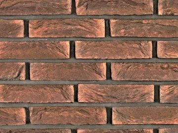 Detailní pohled na červenohnědou klinkerovou cihlovou zeď.