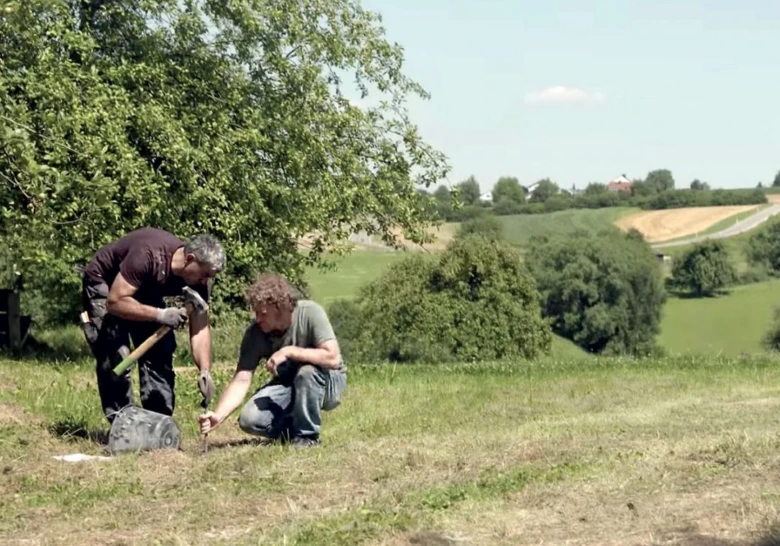 Dva muži připravují bednění základů pro betonování venku na trávníku.