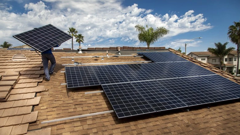 Instalace fotovoltaických panelů na střechu domu.