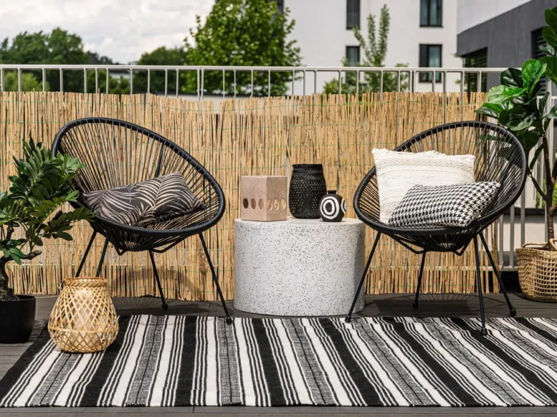 Černobílý pruhovaný koberec na balkóně s židlemi.