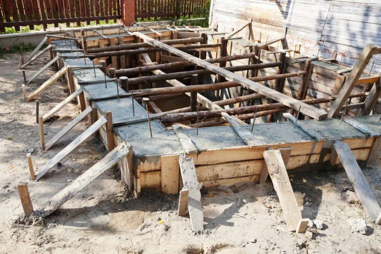 Dřevěné bednění pro betonování základů na písečné ploše.