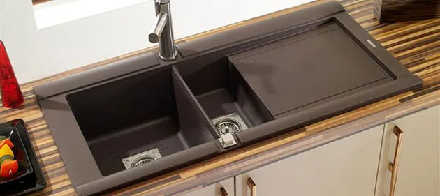Granitový kuchyňský drez s odtokovou deskou nainstalovaný na dřevěné desce.