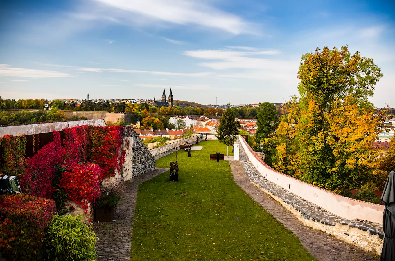 Zpevněná zahrada s výhledem na město a kostely.