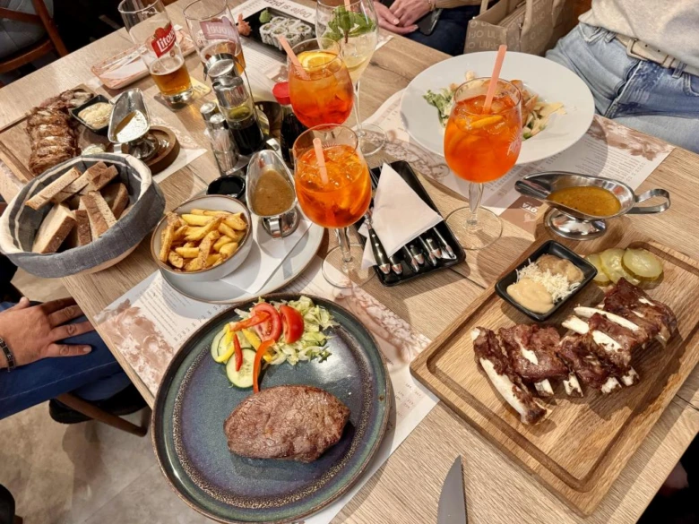 Stůl plný jídla v restauraci s masem, saláty a nápoji.