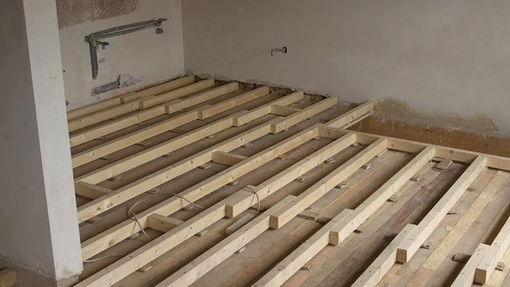 Dřevěné trámy a latě na podlaze během rekonstrukce stropu.