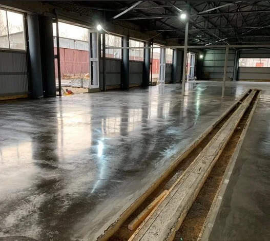 Leštěný betonová podlaha v průmyslovém prostoru s odrazy světla.