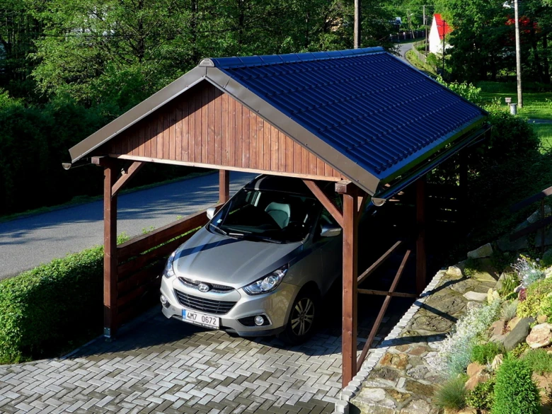 Dřevěný přístřešek pro auto s stříbrným SUV pod tmavou střechou.