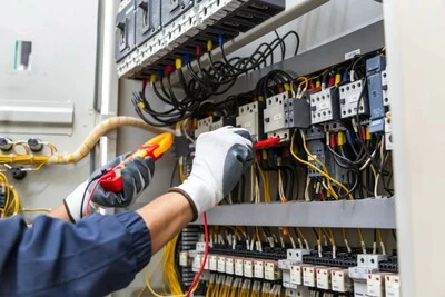 Elektrikář měří napětí v rozvaděči s multimetrem.