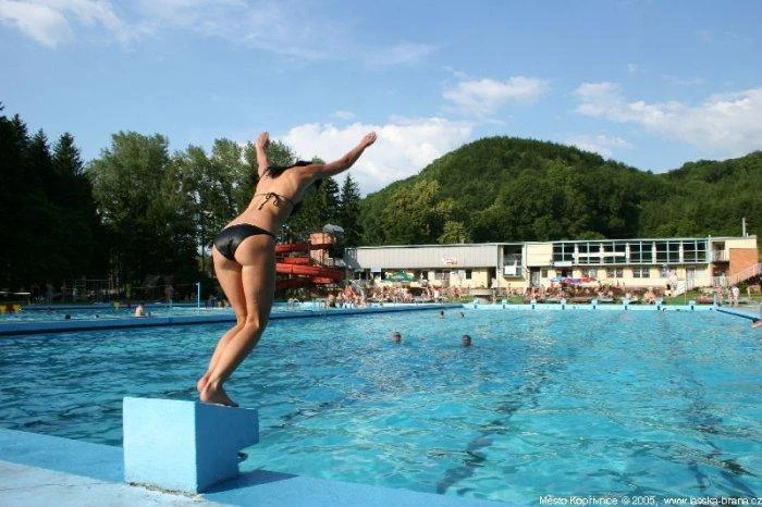 Žena skáče do bazénu v koupališti v Kopřivnici.