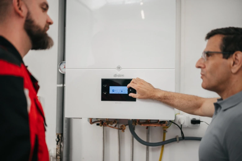 Technik vysvětluje funkci plynového kotle s ohřevem vody zákazníkovi.