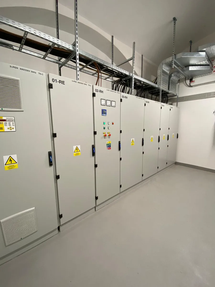 Řada průmyslových elektrických skříní v čistém technickém prostoru.
