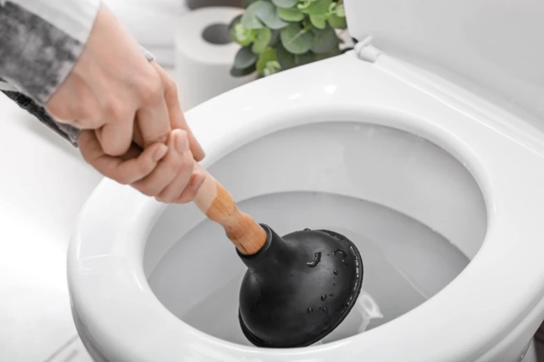 Ruka s hadicí uvolňuje ucpaný záchod.
