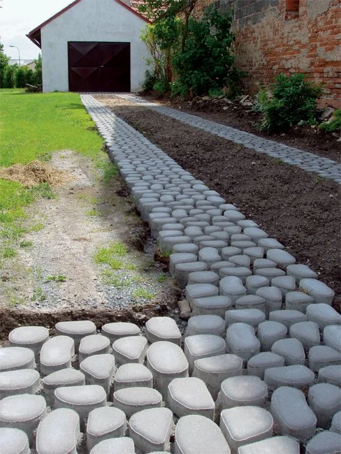 Připravovaná zatravňovací dlažba pro chodník vedle trávníku.