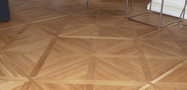 Přehled dokončené parketové podlahy s geometrickým vzorem.
