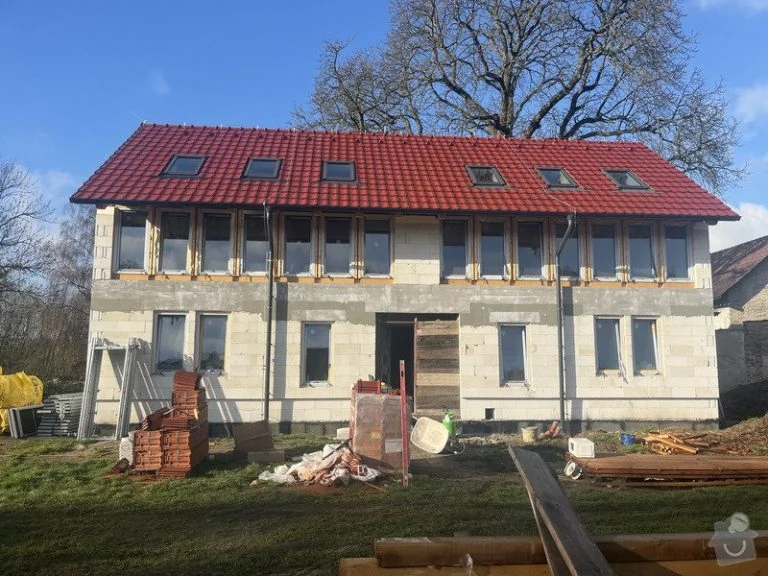 Dvoupatrový dům v hrubé stavbě s červenou střechou a okny.