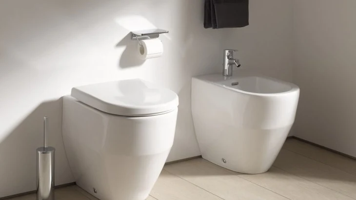 Moderní bílá koupelna s WC a vedlejším umyvákem pro hygienu.