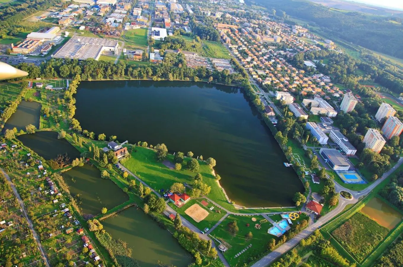 Letadlový pohled na štěrkoviště Otrokovice s koupalištěm a okolní zástavbou.