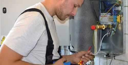 Muž opravuje starý topný systém v domě.