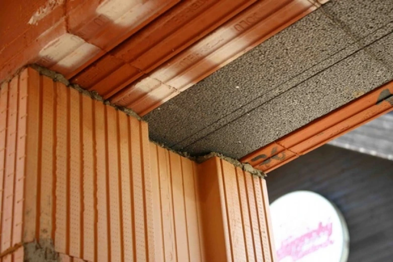 Detail betonu nad oknem s cihlovou zdí