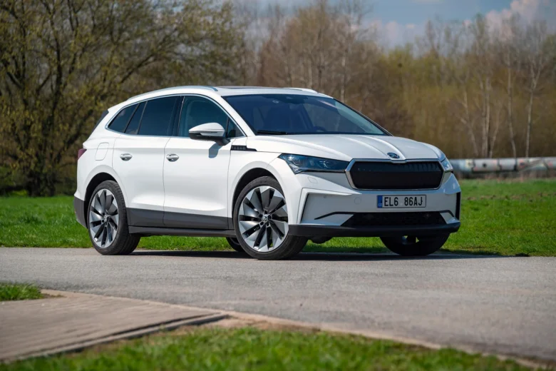 Bílý elektromobil Škoda Enyaq na silnici v přírodě.