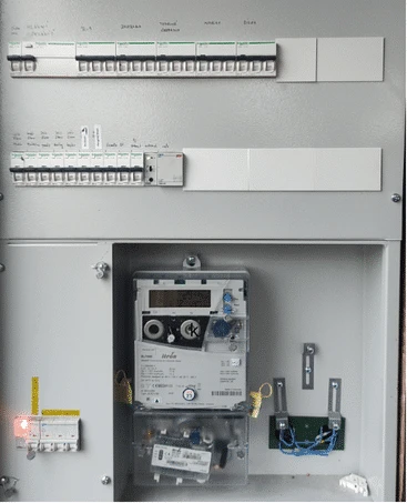 Otevřená elektrická rozvaděč s jističi a měřicím přístrojem.