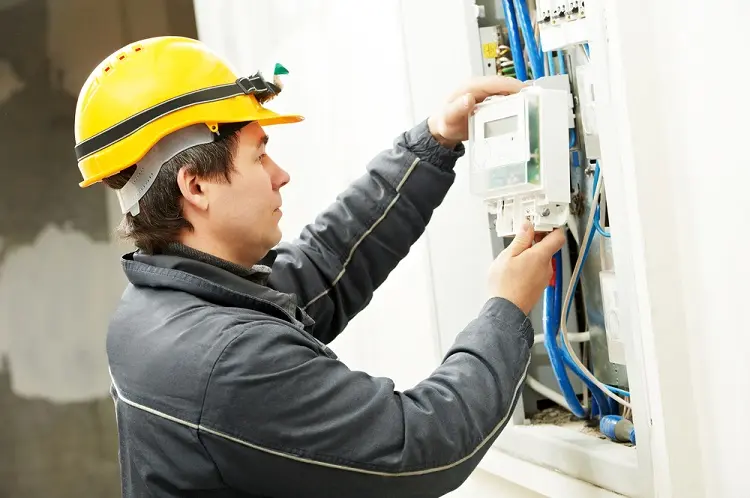 Elektrikář pracuje na elektroměrovém rozvaděči s viditelným zapojením.