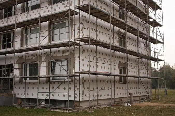 Budova s fasádou zateplovací izolace a schodiště pro stavebníky.