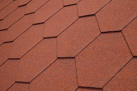 Detail červených střešních šindelů na skloněné střechy.
