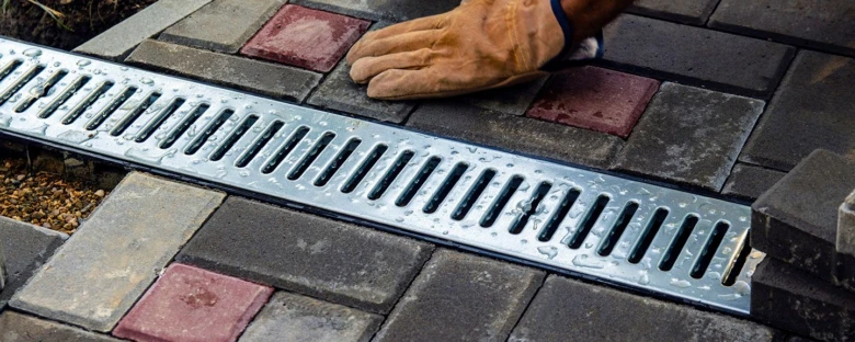 Instalace kovového odvodňovacího žlabu do dlažby v zahradě.