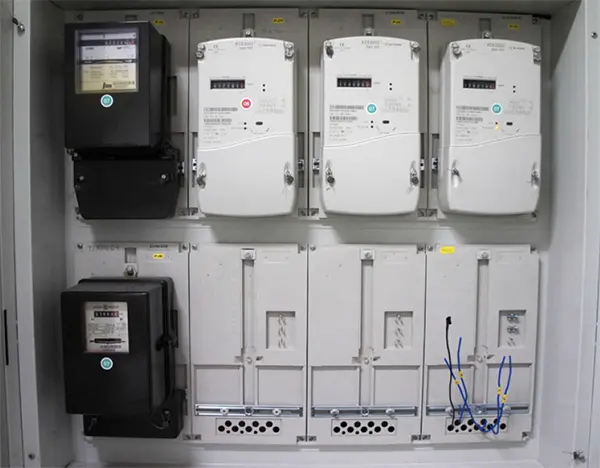 Elektrické měřiče v rozvaděči s viditelným zapojením a kabely.