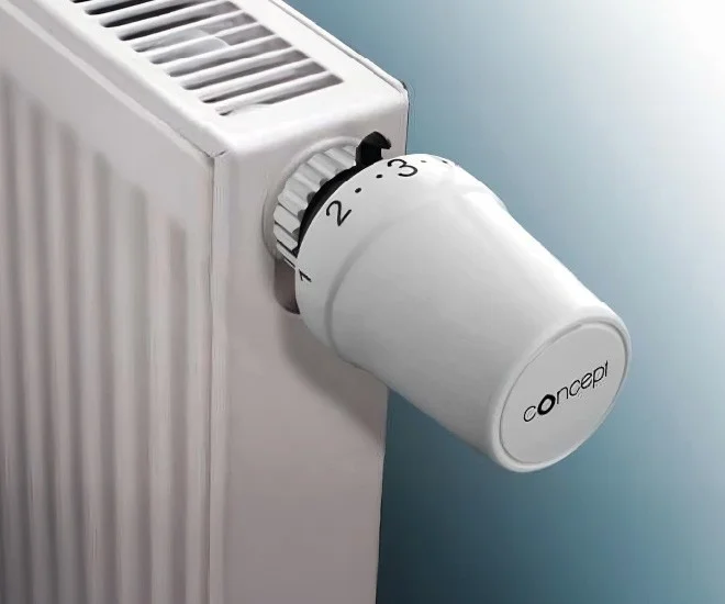 Bílá termostatová hlavice na topení s nastavením teploty.