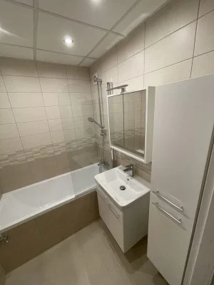 Modernizovaná koupelna s novou vanou, umyvadlem a zrcadlovým skřínem.