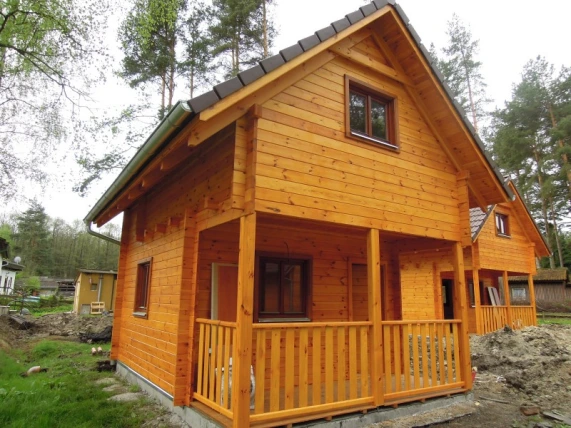 Nově postavená dřevěná chata s terasou v lese.
