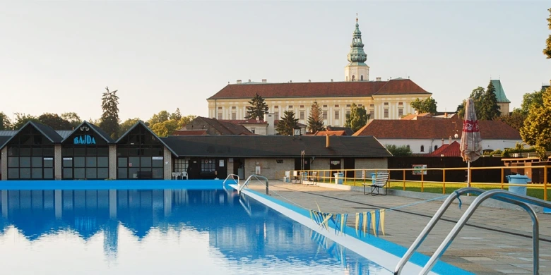 Venkovní bazén v rekreačním areálu s historickým kostelem na pozadí.