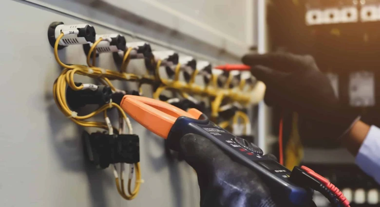 Ruční testování elektrických spojů multimetrem v rozvaděči.