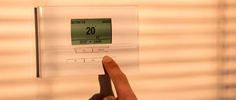 Ruka nastavuje teplotu na termostatu pro úsporu energie v domě.