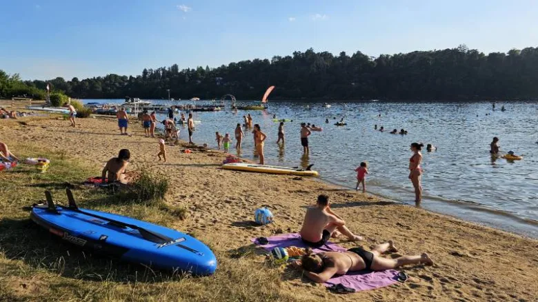 Lidé plavou na koupališti v Praze s paddleboardy.