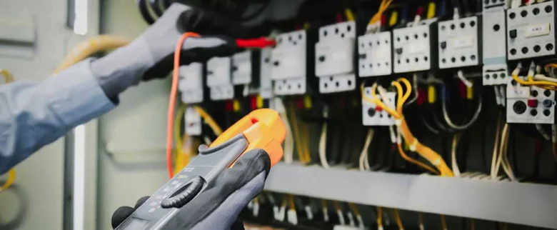 Elektrikář měří napětí v rozvaděči multimetrem.