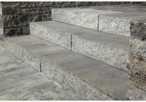 Betonové venkovní schody vedoucí k kamenné zdi.