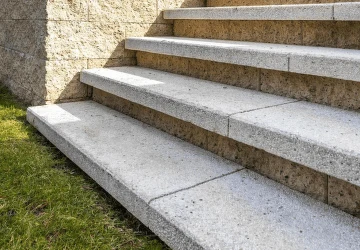 Betonové venkovní schody vedoucí k zdi s trávníkem.