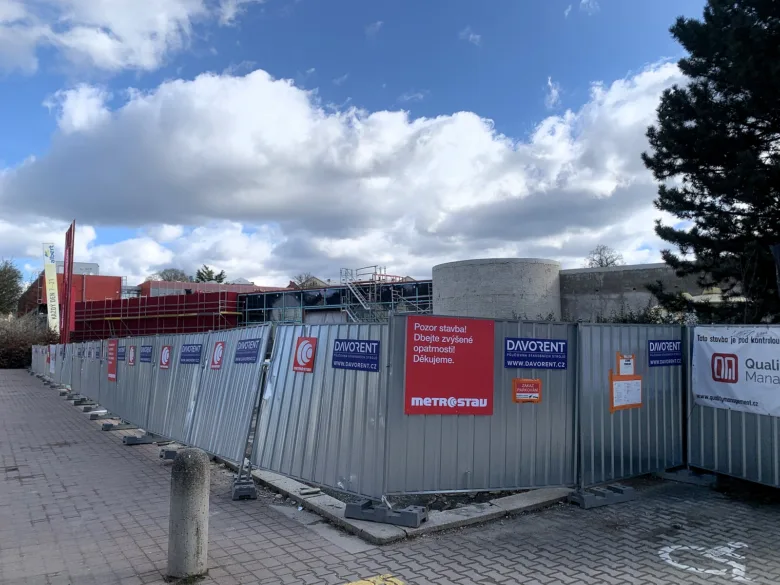 Staveniště v Liberci s reklamami na plotu u bazénu.