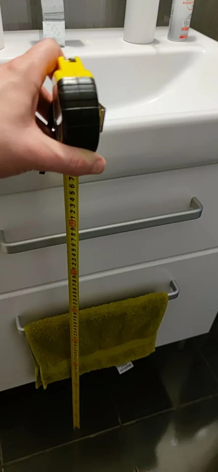Ruční měření výšky umyvadla od podlahy páskou.