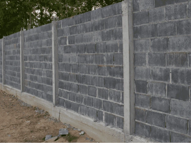 Nová betonová zeď z cihlových bloků s vertikálními bednicími prvky.