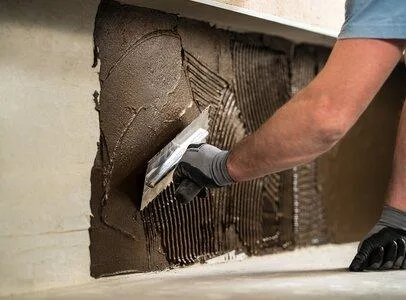 Práce s hydroizolační stěrkou na zdi pomocí špachtle.